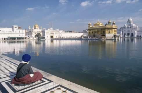 INDIA, Punjab, Amritsar , Sikh man sitting on marble walkway beside the sacred pool surrounding the