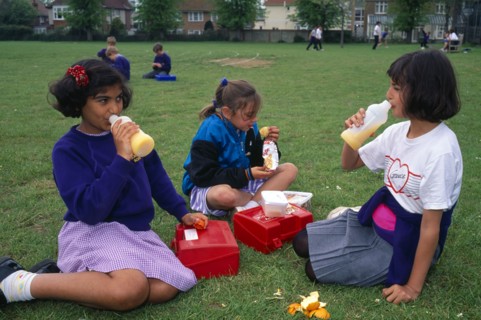 EDUCATION, School, Children, Kids eating packed lunches in the playground.