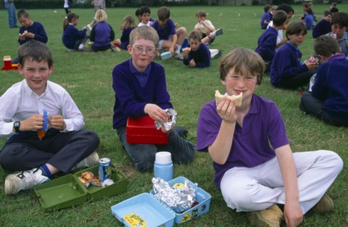 EDUCATION, School, Children, Kids eating packed lunches in the playground.