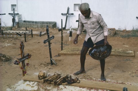 INDIA, Goa, Colva, Man cleaning bones at family grave. The bones are removed and washed to make