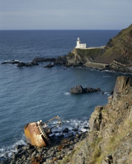 ENGLAND, Devon, North Devon-Hartland Point lighthouse next to rugged coast with a shipwrecked boat
