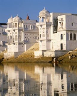 INDIA, Rajasthan, Pushkar, White temple on shore of Pushkar Lake and reflected in water.