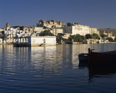 INDIA, Rajasthan, Udaipur, City Palace with reflections and silhouetted boat