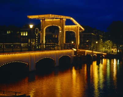 HOLLAND, North, Amsterdam, Magere Brug or Skinny Bridge illuminated at night with lights reflected