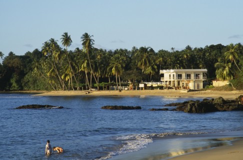 WEST INDIES, Tobago, Grafton Beach, People standing in sea beside sandy beach with white painted