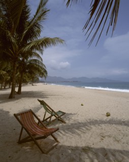 VIETNAM, South, Nha Trang, "Beach,golden sand,two empty deckchairs,palm trees,distant hills "