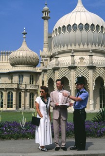 ENGLAND, East Sussex, Brighton, Policeman giving tourist couple directions outside the Royal