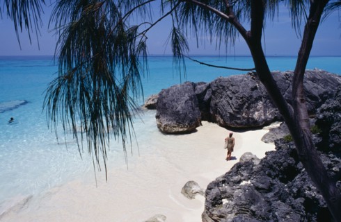 BERMUDA, Whale Bone Bay Beach, Female tourist in dress walking along the beach towards rocks seen