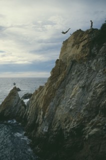 MEXICO, Guerrero, Acapulco, Cliff diver in mid air with sea below