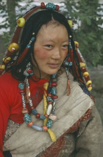 CHINA, Qinghai, Golmud, Tibetan woman in traditional clothes wearing beads in hair and around neck