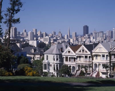 USA, California, San Fransisco, Alamo Square with city skyline beyond a row of timber town houses