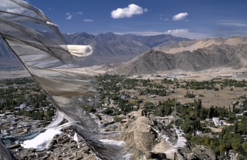 INDIA, Ladakh, Leh Valley , Prayer flags blowing in the wind above village and mountainous terrain