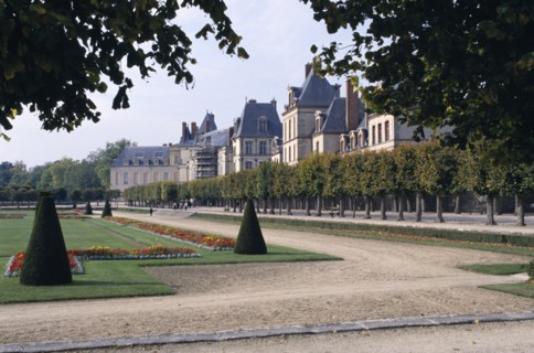 FRANCE, Fontainebleau, Palace and gardens framed by tree branches