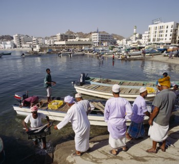 OMAN, Capital Area, Matrah, Fish Souk with locals unloading a catch at jetty. Boats and the