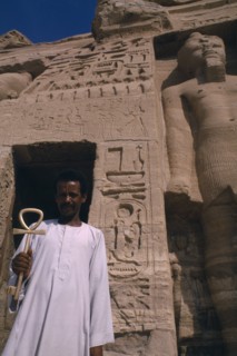 EGYPT, Abu Simbel, Man holding key of life in front of temple statue and hieroglyphics
