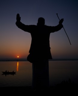 INDIA, Uttar Pradesh, Varanasi, Silhouette at sunset of a Holy Man on the banks of the River Ganges