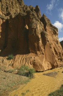 CHINA, Quinghai, Yellow River tributary flowing past large red rocks