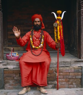 NEPAL, Kathmandu, Full length portrait of holy Man dressed in red.