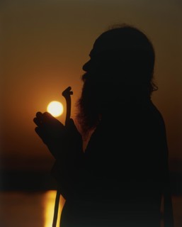 INDIA, Uttar Pradesh, Varanasi, Silhouette of Holy Man praying on the banks of the River Ganges at