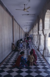 INDIA, Delhi, "Sikh pilgrims sitting on long, colonnaded temple passage-way with black and white
