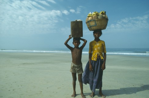 INDIA, Goa, Colva, Boy and girl from Karnataka on beach carrying fruit and drinks to sell to