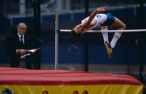 10000115 SPORT Athletics High Jump Competitor in junior athletics championships clearing bar in high jump.