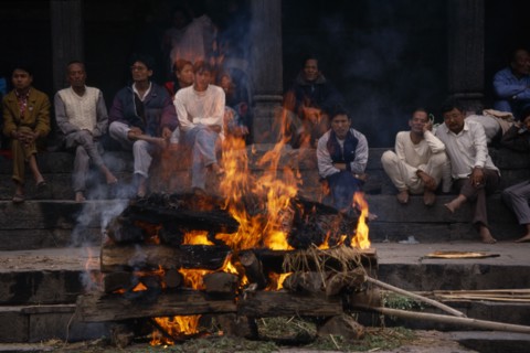 NEPAL, Kathmandu, Hindu cremation in Pashupatinath Temple.  Burning wood funeral pyre with