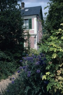 FRANCE, Normandy, Eure , Giverny. Claude Monet’s house with shuttered windows seen through garden