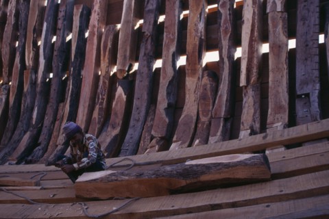 INDIA, Gujarat, Veraval, Shipbuilding.  Man working on interior shell of boat.