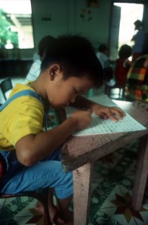 VIETNAM, Ho Chi Minh City, Child writing at a desk in an Agent Orange Orphanage.