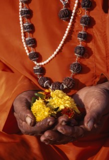 INDIA, Maharashtra, Nasik, Cropped shot of figure in orange robes and wearing prayer beads.  Close