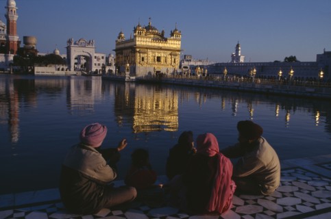 INDIA, Punjab, Amritsar, Golden Temple.  General view with pilgrim group sitting beside sacred pool