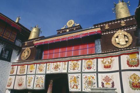 TIBET, Lhasa, Jokhang Temple, Golden Wheel of Dharma on roof of building covered in hanging fabrics