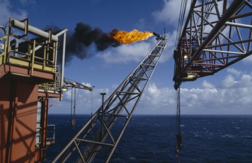 INDUSTRY, Factory, Oil Rig, Burning Off Gas. View along long pipe structure jutting out over the