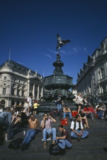 ENGLAND, London, Picadilly Circus with people congregating on the steps surrounding the base of