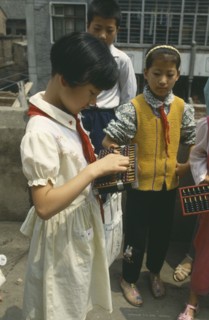 CHINA, Shaanxi, Xian, Schoolgirl standing with other children using an abacus.