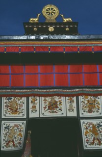 TIBET, Lhasa, Jokhang Temple, Golden Wheel of Dharma on roof of building covered in hanging fabrics