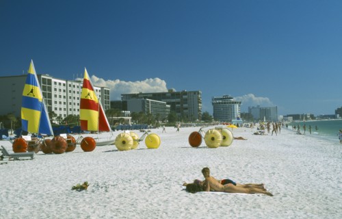 USA, Florida, St.Petersburg, "Sunbathers, Hobbie cats and pedalos on white sand beach with city