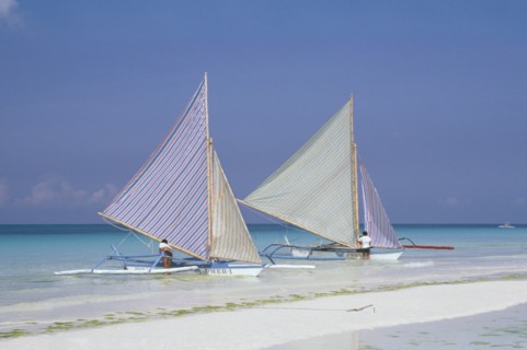 PHILIPPINES, Visayan Islands, Boracay Island, Two outriggers with striped sails moored on the edge