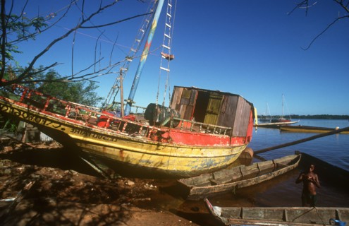 FRENCH GUIANA, St Laurent, Beached fishing boat with boy in shallow water