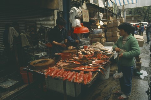 CHINA, Guangdong, Guangzhou, Fish stall in the market with vendor and customer.