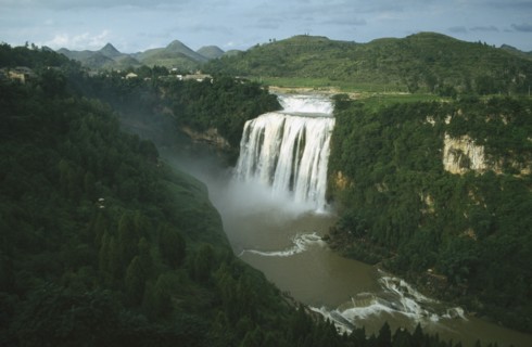 CHINA, Guizhou, Huangguoshu Falls seen from a distance within lush green surrounding landscape
