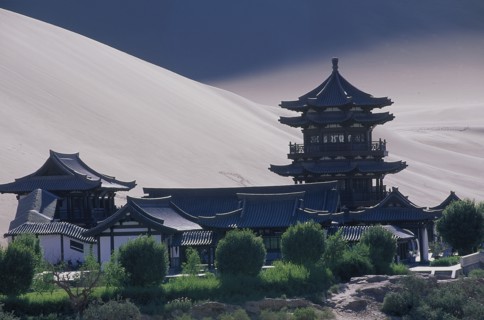 CHINA, Gansu, Dunhuang, Silk Route with a Buddhist Temple and sand dunes beyond