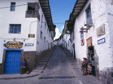 PERU, Cusco Department, Cusco, View up a narrow street between white painted houses.   Woman and