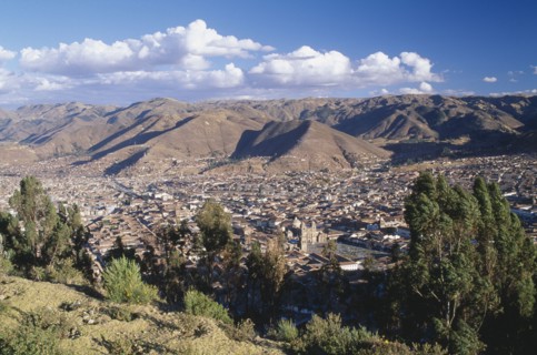 PERU, Cusco Department, Cusco, View over trees and the city of Cusco to the mountains beyond.