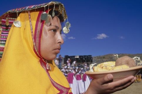 PERU, Cusco Department, Cusco, "Woman in traditional headress carrying an offering of food during