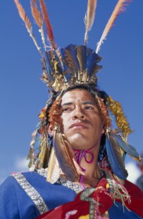PERU, Cusco, Male figure in traditional costume and feathered headress at Inti Raymi.  Head and