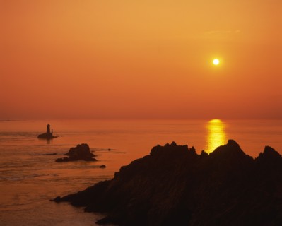 FRANCE, Brittany, Finistere, Near Audierne.  Pointe du Raz at sunset.  Rocks silhouetted against an