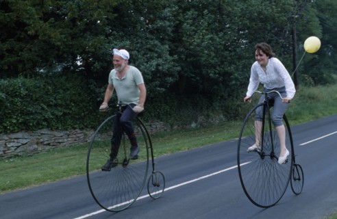 20005306 SPORT Cycling Bikes Man and woman riding old Penny Farthing Bicycles