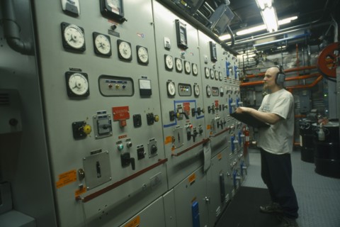 ANTARCTICA, South Pole, US Amundsen-Scott South Pole Station.  Man with clipboard at contol panels